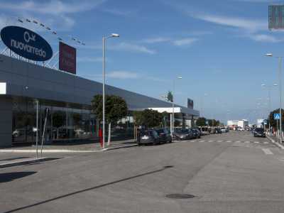 Alla fine della via svoltiamo a destra percorrendo un ponticello che attraversa il �canalone� e ci porta direttamente nei parcheggi della prima ampia area dedicata allo shopping, dominata da capannoni rettangolari in continuo aumento